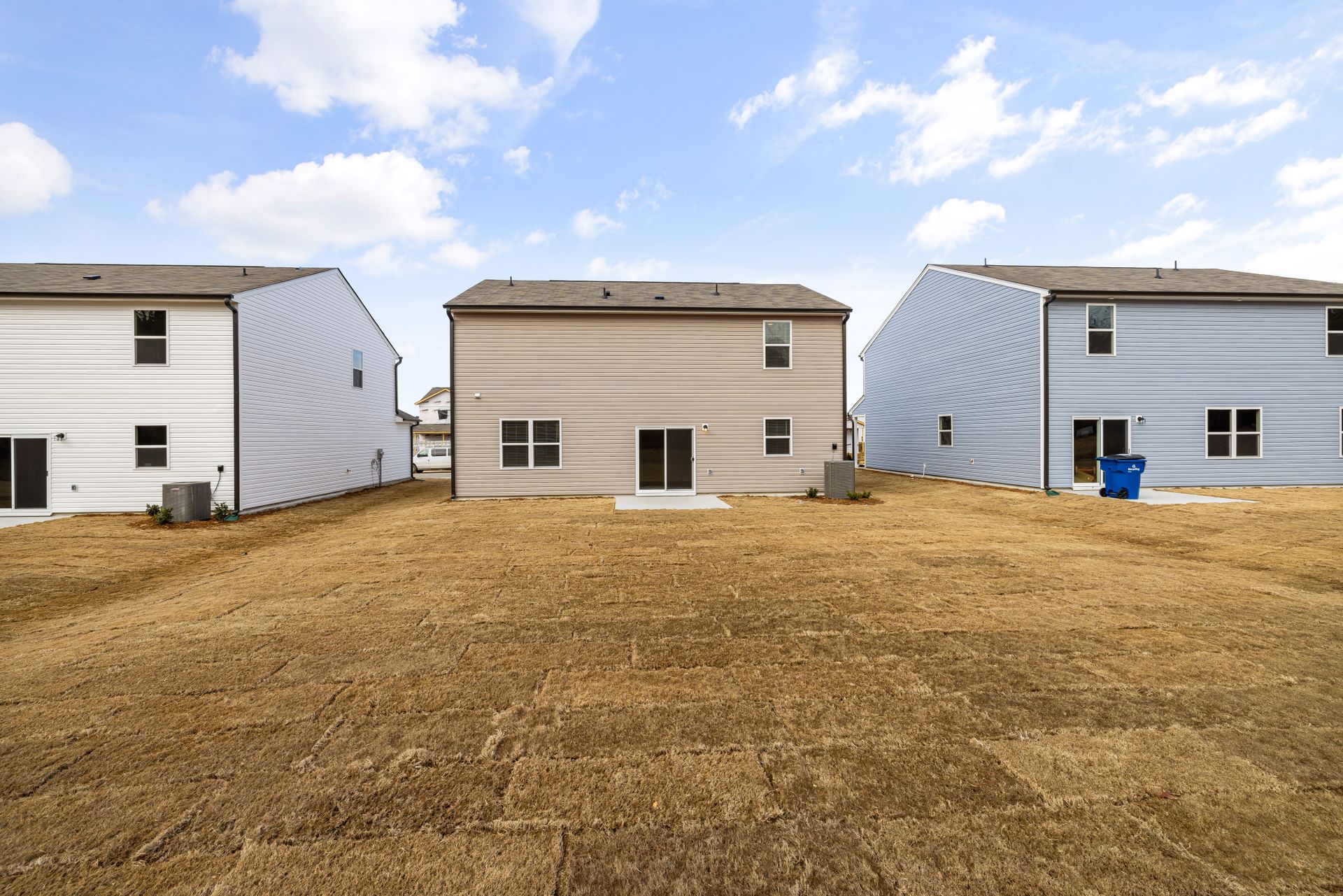 Bare, patchy lawn behind a new house