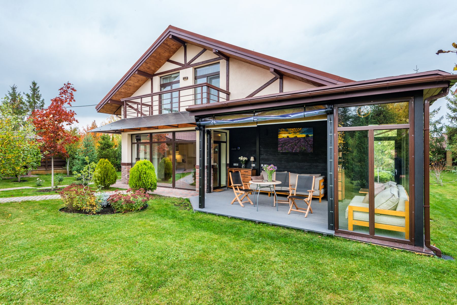 Cottage with a veranda overlooking a green lawn and trees